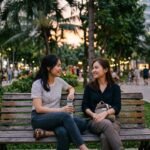 Hai người bạn ngồi trò chuyện ở công viên lúc chiều muộn, thể hiện sự lắng nghe và kết nối nhẹ nhàng