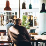 Một người ngồi yên trong quán cà phê, ánh sáng dịu qua khung cửa sổ