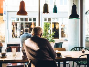 Một người ngồi yên trong quán cà phê, ánh sáng dịu qua khung cửa sổ